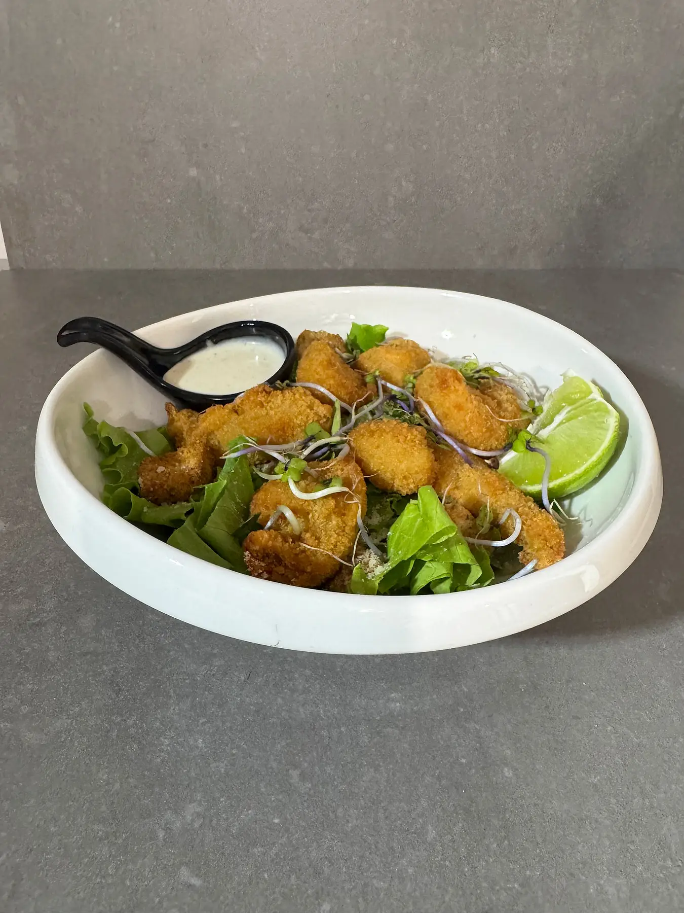 Crispy fried fish salad with a lime wedge and dipping sauce