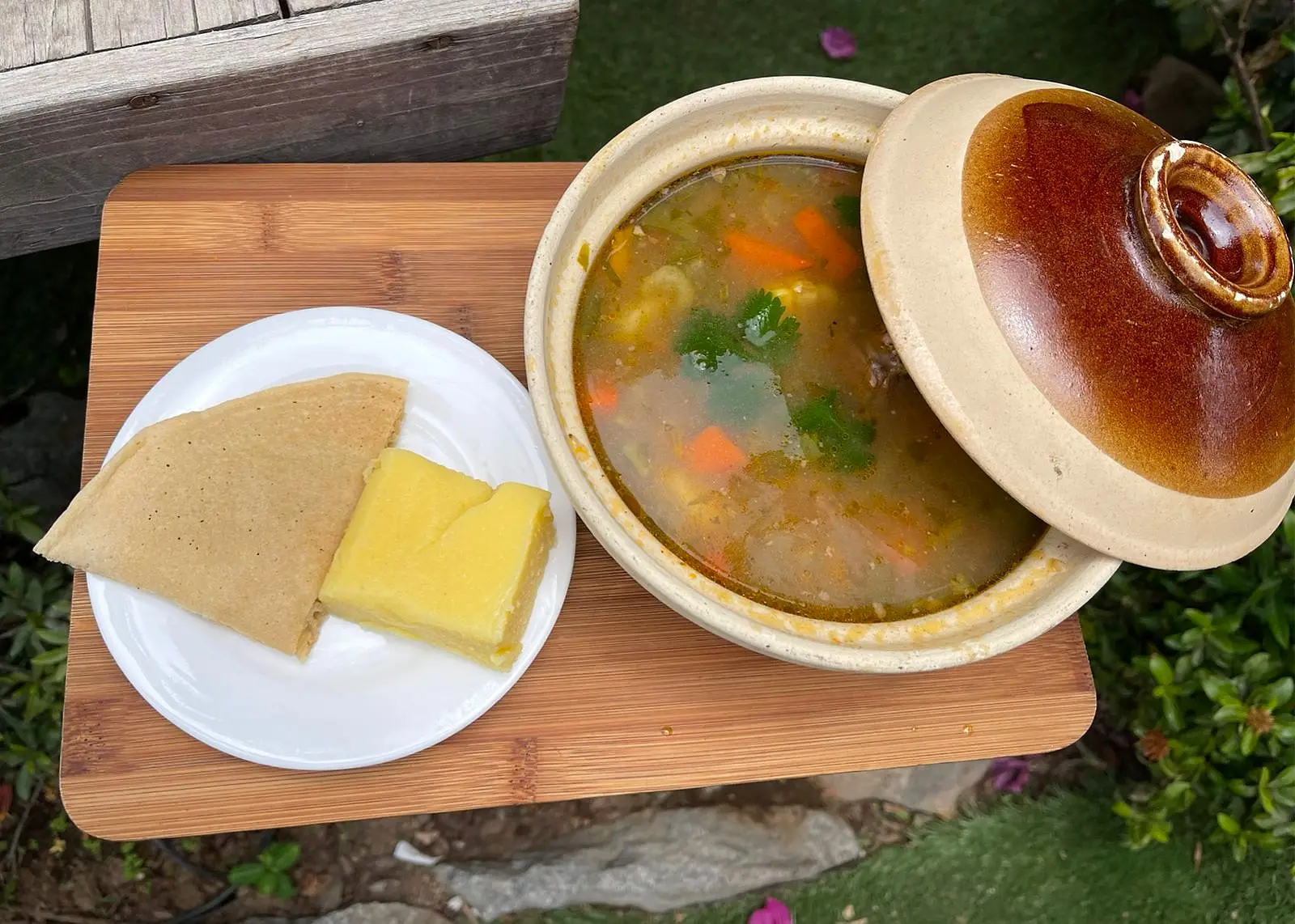 Homestyle soup in a clay pot served with arepa and cheese